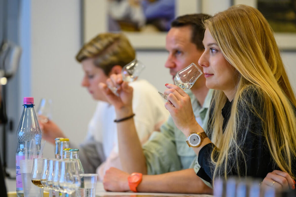 Teilnehmerinnen und Teilnehmer eines Tastings riechen an ihren Gläsern